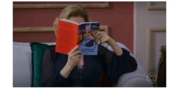 Cena da atriz Beatriz Segall, como a personagem Odete Roitman, segurando o livro "O Perigo de Estar Lúcida" em frente ao rosto.