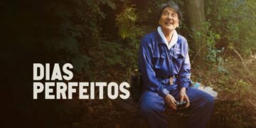 O ator Kōji Yakusho no filme "Dias Perfeitos", sentado em um banco em um parque, sorrindo e olhando para cima.