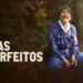 O ator Kōji Yakusho no filme "Dias Perfeitos", sentado em um banco em um parque, sorrindo e olhando para cima.