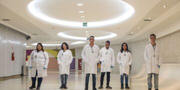 Grupo de jovens em laboratório, participantes do Programa Jovem Aprendiz Petrobras 2025, com uniformes de trabalho.
