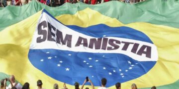 Multidão reunida em protesto com bandeira gigante do Brasil e faixa “Sem Anistia” ao centro.