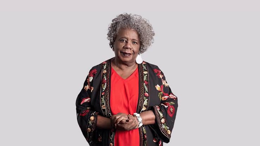 Conceição Evaristo de cabelos grisalhos, vestindo blusa vermelha e kimono preto com flores, sorrindo para a câmera
