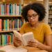 Jovem lendo livro de autores vivos em biblioteca