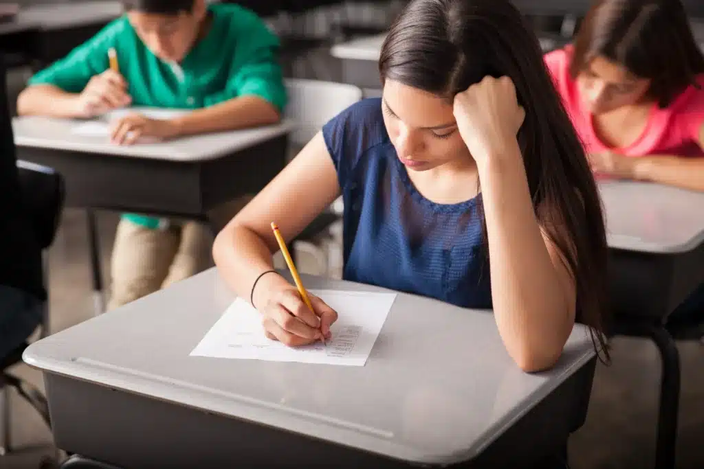 Estudante concentrada durante prova de Língua Portuguesa no Enem, com foco na interpretação de texto.