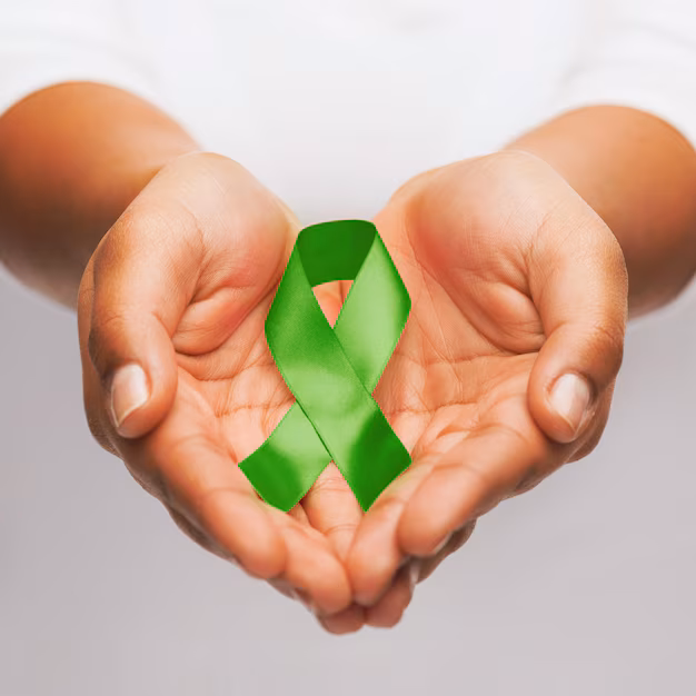 Mãos femininas segurando fita verde de conscientização sobre inclusão e doação de órgãos