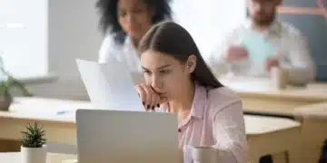 Jovem trabalhando em escritório, com foco em leitura de documentos, ilustrando o estágio INSS 2025.
