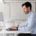 Homem jovem em ambiente de escritório, trabalhando em seu notebook. Representa um profissional em home office, um dos temas centrais no debate sobre monitoramento e produtividade