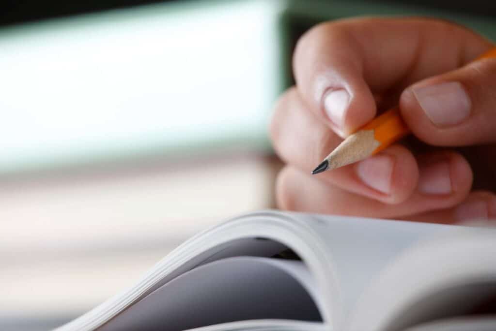 Estudante com lápis na mão, focado na leitura de um livro, simbolizando o estudo para o vestibular.