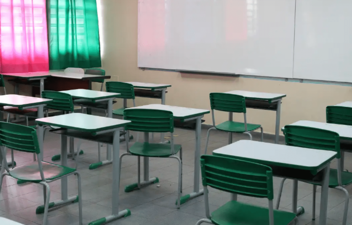 Professores de 16 estados pedem mais filosofia e sociologia nas escolas. Sala de aula com carteiras verdes vazias em frente a um quadro branco.