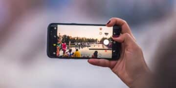 Pessoa gravando ou fotografando uma cena externa com smartphone na horizontal, evidenciando a qualidade da câmera móvel em fotos.