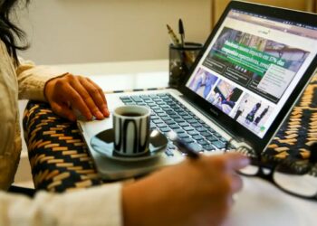 Pessoa pesquisando cursos online e escrevendo anotações durante o estudo.