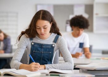 Imagem ilustrativa de estudante escrevendo concentrada durante simulado de redação.