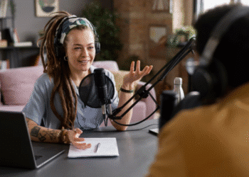 Apresentadora de podcast com microfone e fones de ouvido, gesticulando em um estúdio, ilustrando as dicas para criar e engajar uma audiência do zero.