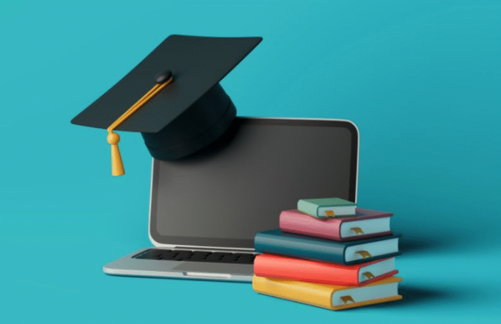 Chapéu de formatura sobre notebook ao lado de pilha de livros coloridos.