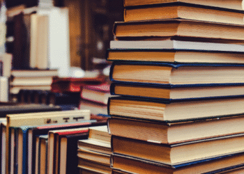 Pilha de livros empilhados sobre uma mesa em ambiente de leitura.