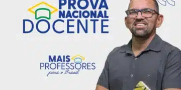 Imagem de um homem sorrindo com óculos, segurando um livro.