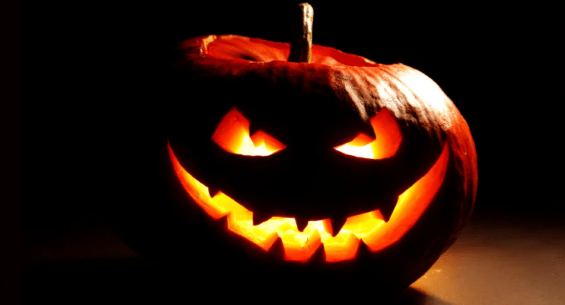 Abóbora esculpida com rosto assustador iluminada por dentro, símbolo tradicional do Halloween.