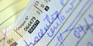 Detalhe de cheque manuscrito com valor preenchido por extenso, prática comum para evitar fraudes