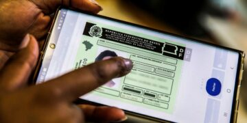Uma mão manuseando um celular que exibe a Carteira Nacional de Habilitação (CNH) Digital. A imagem representa o programa do Governo que oferece cursos gratuitos para tirar a primeira CNH.