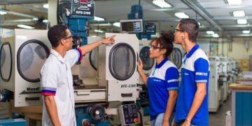 Funcionários do Senai interagindo com máquinas em um ambiente industrial, com foco em segurança e aprendizado técnico.