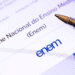 Tela com o logo do Enem e uma caneta apontando para o texto “Exame Nacional do Ensino Médio”.