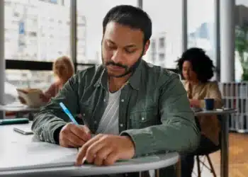 Homem estudando em ambiente tranquilo, com foco no processo de aprendizado, para entender como se preparar para a prova do PND.