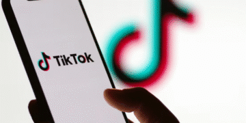 Pessoa segurando celular com o aplicativo TikTok aberto na tela.