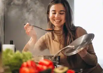 Mulher sorrindo enquanto experimenta um prato em uma aula de culinária internacional, explorando novas técnicas e receitas.