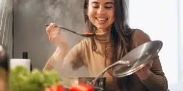 Mulher sorrindo enquanto experimenta um prato em uma aula de culinária internacional, explorando novas técnicas e receitas.