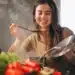Mulher sorrindo enquanto experimenta um prato em uma aula de culinária internacional, explorando novas técnicas e receitas.