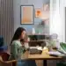 Mulher trabalhando em casa com um computador portátil, mantendo uma xícara de café, em ambiente tranquilo e moderno