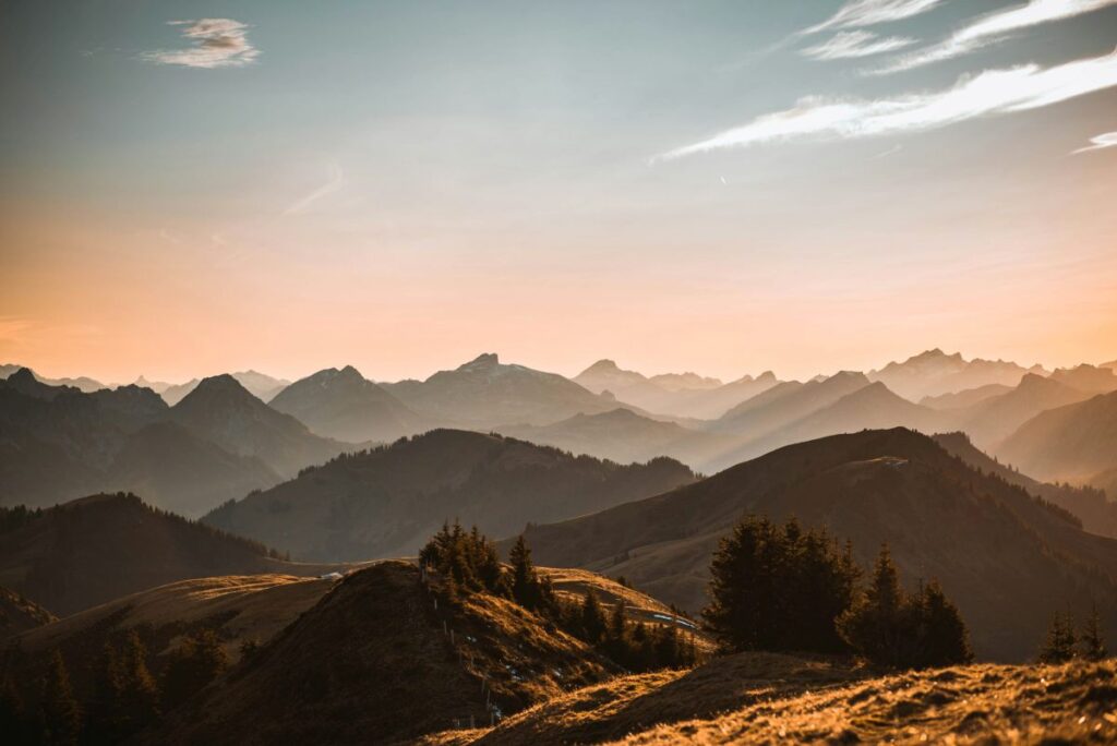 Paisagem montanhosa ao entardecer, com montanhas e árvores, ilustrando a formação de diminutivos de 'montanha' na língua portuguesa.