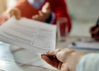 Pessoa entregando currículo durante entrevista de emprego, em um ambiente de escritório