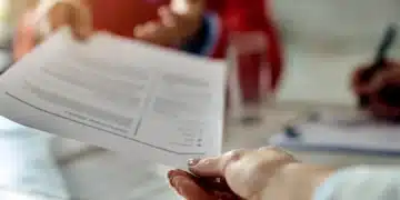 Pessoa entregando currículo durante entrevista de emprego, em um ambiente de escritório