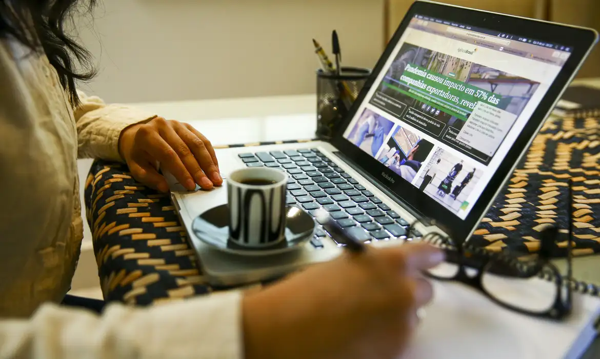 Trabalho remoto com laptop e café na mesa Pessoa usando laptop para trabalhar remotamente com café expresso em xícara preta e branca ao lado