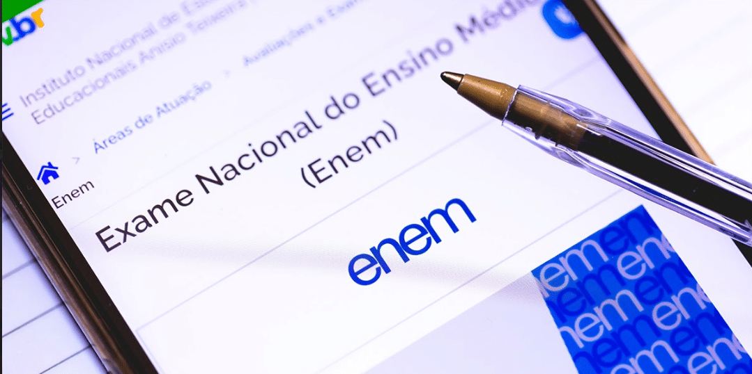 Smartphone exibindo página do INEP sobre o Exame Nacional do Ensino Médio (Enem) com caneta apontando para a tela e fundo com repetições de "enem".