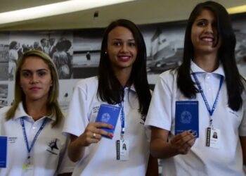 Jovens aprendizes, segurando suas carteiras de trabalho, simbolizando o direito ao 13º salário e a inclusão no programa de aprendizagem.