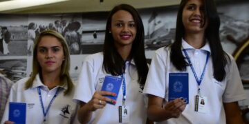 Jovens aprendizes, segurando suas carteiras de trabalho, simbolizando o direito ao 13º salário e a inclusão no programa de aprendizagem.