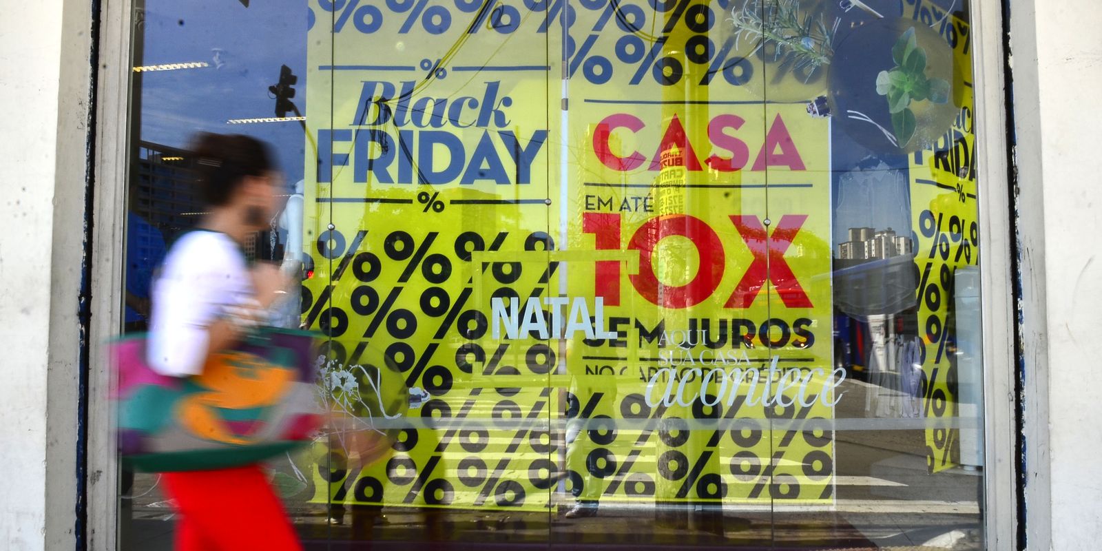 Vitrine de loja com cartazes de promoção da Black Friday e do Natal, indicando grandes descontos. O artigo lista dicas para compras seguras e inteligentes no evento.