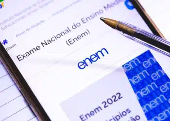 Tela de celular aberta no site oficial do Exame Nacional do Ensino Médio (Enem) com uma caneta, representando a consulta de notas e resultados para treineiros.