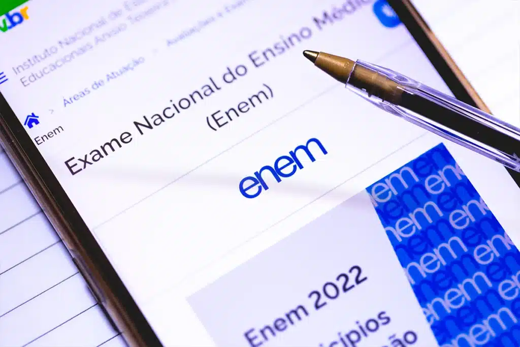 Autorregulação Emocional e Estratégia de Estudo para o ENEM 2025 Imagem de uma tela de celular exibindo o site oficial do Exame Nacional do Ensino Médio (ENEM) com uma caneta sobre a tela, representando o foco e planejamento na reta final de estudos.