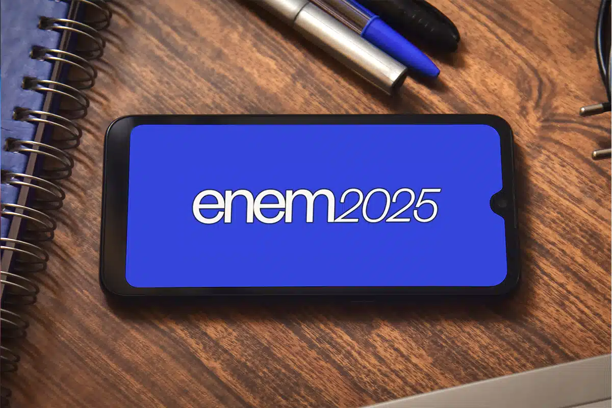 ENEM 2025 e o Impacto da COP 30 na Amazônia Um smartphone com a inscrição "enem2025" na tela, sobre uma mesa com cadernos e canetas, simbolizando o estudo e as datas do ENEM que serão alteradas para algumas regiões devido à COP 30 em Belém.