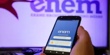 Pessoa segurando celular com aplicativo do ENEM aberto na tela e logo do ENEM ao fundo