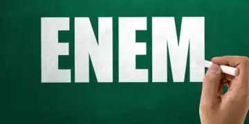 Uma mão escrevendo "ENEM" com giz branco em um quadro-negro verde. A imagem simboliza a preparação para o Exame Nacional do Ensino Médio, especialmente na disciplina de Matemática.