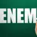 A sigla ENEM escrita em giz branco sobre um quadro-negro verde, com uma mão segurando um pedaço de giz, representando o edital e as regras imutáveis do exame.
