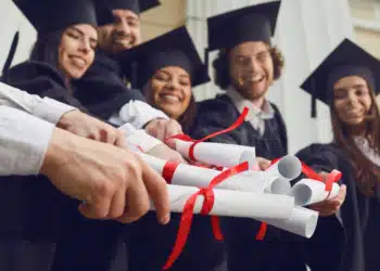 Formandos em comemoração seguram seus certificados, simbolizando o diploma de curso técnico e a entrada no mercado de trabalho.