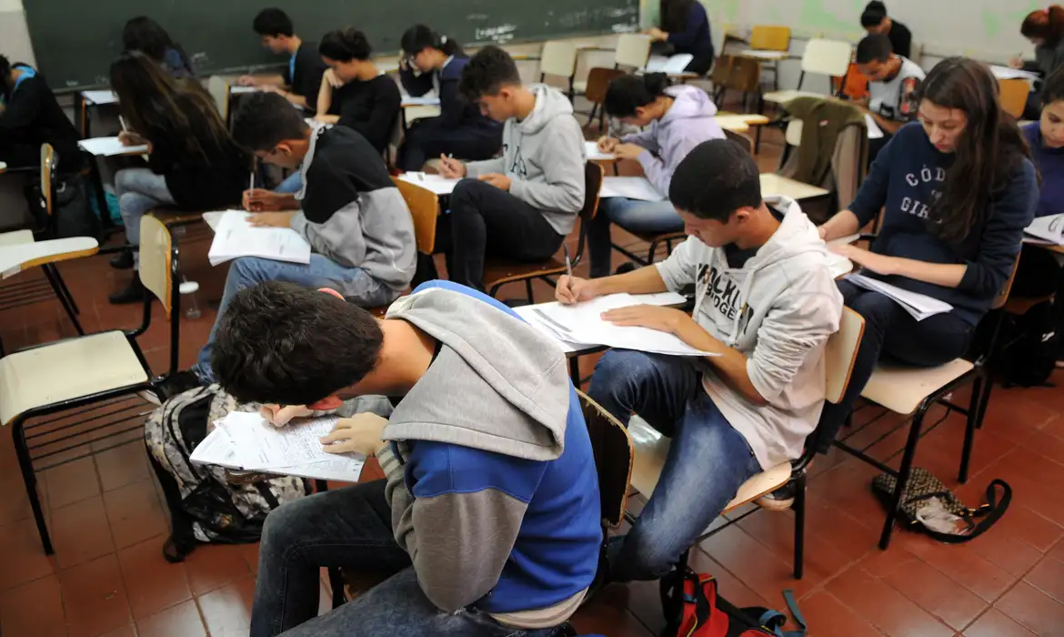 Alunos jovens fazendo prova em sala de aula Alunos jovens fazendo prova em sala de aula