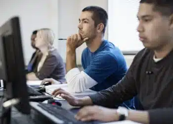 Grupo de estudantes em um curso técnico, concentrados e utilizando computadores.