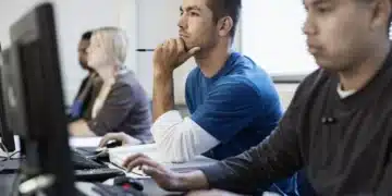 Grupo de estudantes em um curso técnico, concentrados e utilizando computadores.