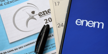 Prova do ENEM, caneta e celular com o aplicativo do exame sobre uma mesa, representando a preparação para o ENEM 2025.